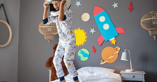 Boy Jumping on a Bed While Wearing a Helmet